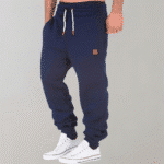 Donkerblauwe joggingbroek voor heren met witte trekkoorden en bruin logo-embleem, gecombineerd met witte sneakers. Comfortabele sportkleding.