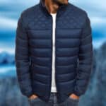 Donkerblauwe gewatteerde herenjas, waterdicht, met ruitpatroon op de schouders, gedragen door een man. Perfect voor winter en outdoor activiteiten.