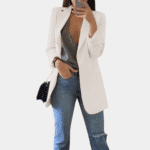 Witte damesblazer, elegant en stijlvol, gecombineerd met een grijze top en blauwe jeans. Perfect voor modieuze casual en zakelijke outfits.