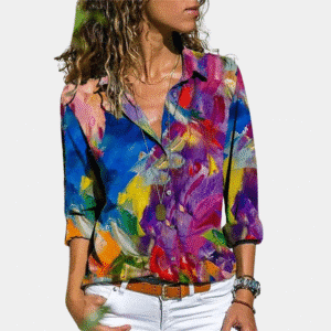 Vrouw in kleurrijke blouse met abstract bloemenpatroon, lange mouwen en kraag, gecombineerd met witte broek. Modieuze dameskleding.