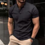 Zwarte herenpolo met korte mouwen, gedragen door een man met gespierde armen. Stijlvolle casual outfit, ideaal voor modebewuste mannen.