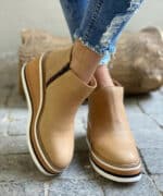 Lichtbruine enkellaarzen voor dames met witte zool, gedragen met gescheurde jeans. Modieuze, comfortabele schoenen voor dagelijks gebruik.