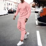 Man in roze trainingspak en witte sneakers loopt op straat. Stijlvolle sportkleding, casual mode, stedelijke achtergrond.
