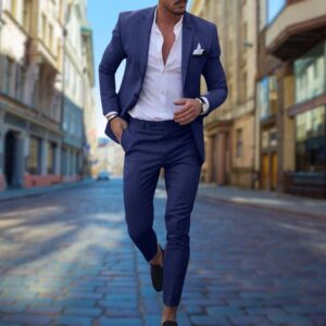 Man in blauw slim fit pak loopt in stedelijke straat, witte overhemd en pochet, stijlvolle herenkleding, mode voor zakenlieden.
