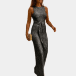 Vrouw in glinsterende zilveren jumpsuit met riem, elegante avondkleding, trendy mode voor dames, perfect voor feestelijke gelegenheden.