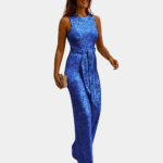 Vrouw in blauwe glitter jumpsuit met riem, elegante avondkleding, gouden clutch, mode voor dames, feestelijke outfit, trendy kledingstijl.