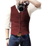 Man in rood gilet met knopen, witte overhemd en blauwe jeans, houdt camera vast. Stijlvolle herenkleding, casual mode, fotografie-accessoire.