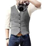 Grijze herengilet met knopen, gedragen over een witte overhemd, gecombineerd met blauwe jeans. Stijlvolle casual outfit voor herenmode.
