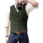 Man in olijfgroen gilet met knopen, witte overhemd en blauwe jeans, houdt camera vast. Stijlvolle herenkleding, casual mode, fotografie.