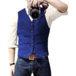 Man in blauwe gilet met knopen, witte overhemd en jeans, houdt camera vast. Stijlvolle herenkleding, casual mode, fotografie-accessoire.
