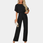 Stijlvolle zwarte dames jumpsuit met korte mouwen en strikceintuur, gecombineerd met een elegante witte clutch. Perfect voor modieuze gelegenheden.