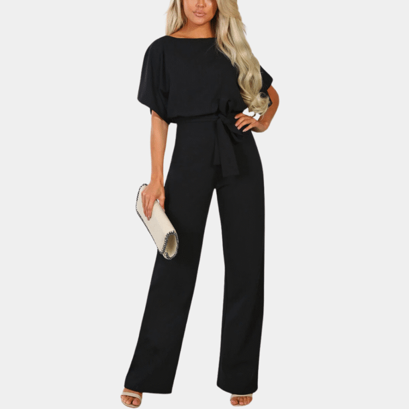 Stijlvolle zwarte dames jumpsuit met korte mouwen en strikceintuur, gecombineerd met een elegante witte clutch. Perfect voor modieuze gelegenheden.