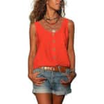 Vrouw in rode mouwloze top met knopen, denim shorts en bruine riem. Casual zomeroutfit, boho-stijl, kleurrijke kettingen.