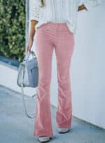 Vrouw draagt roze flared broek en witte trui, met grijze handtas. Modieuze dameskleding, trendy outfit, casual stijl.