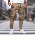 Beige cargobroek voor heren, casual stijl, met elastische tailleband en zakken, gedragen met witte sneakers. Perfect voor stedelijke mode.
