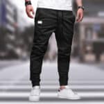Zwarte cargobroek voor heren, casual streetwear stijl, met elastische tailleband en enkelboorden, gedragen met witte sneakers op een stedelijke achtergrond.
